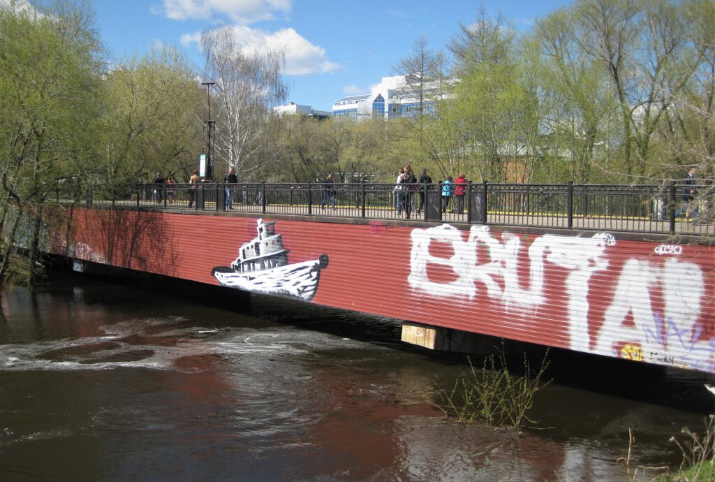 Fußgängerbrücke über den Isset in Jekaterinburg. Graffiti eines Boots auf rotem Hintergrund der Fassade. 
