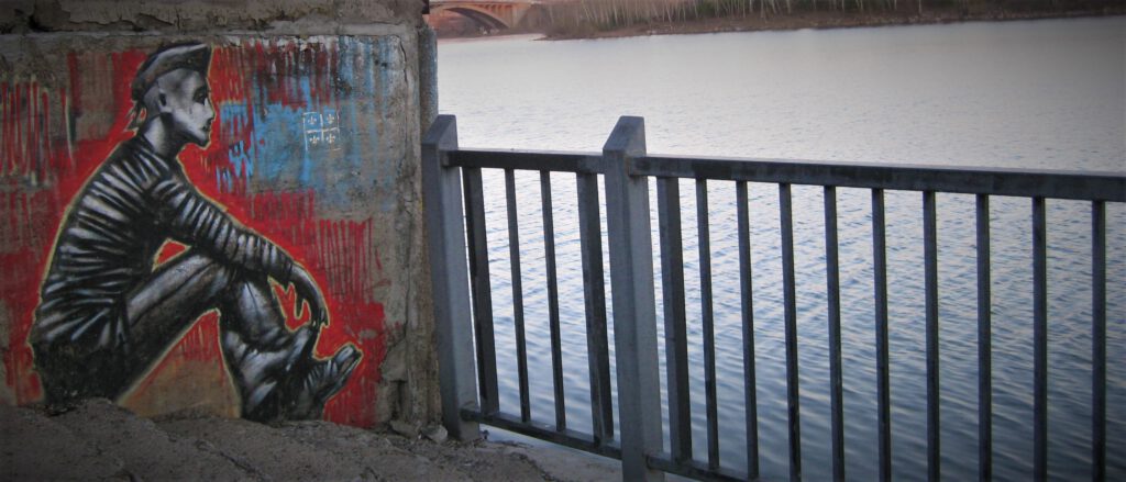 Krasnojarsk Streetart. Grafitti mit sitzendem Jugendlichen, der in Richtung Jenissei schaut. 