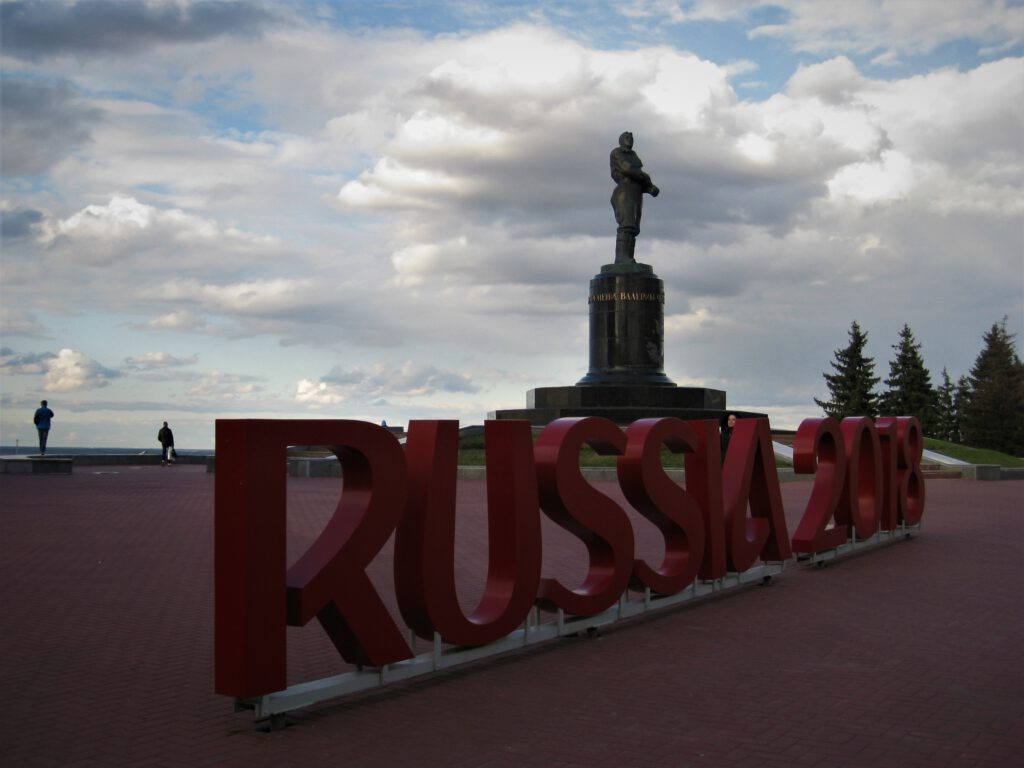 Große aufgestellter Schriftzug "Russia 2018" in roten Buchstaben vor der Statue von Waleri Tschkalow.  