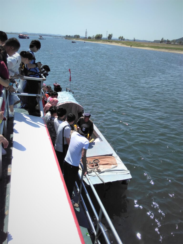 Touristen sprechen von Boot zu Boot mit dem nordkoreanischen Händler auf dem Yalu. 