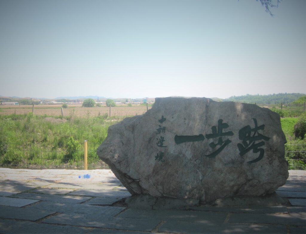 Grenzstein zwischen China und Nordkorea. Aufschrift "Einen Schritt nach drüben".