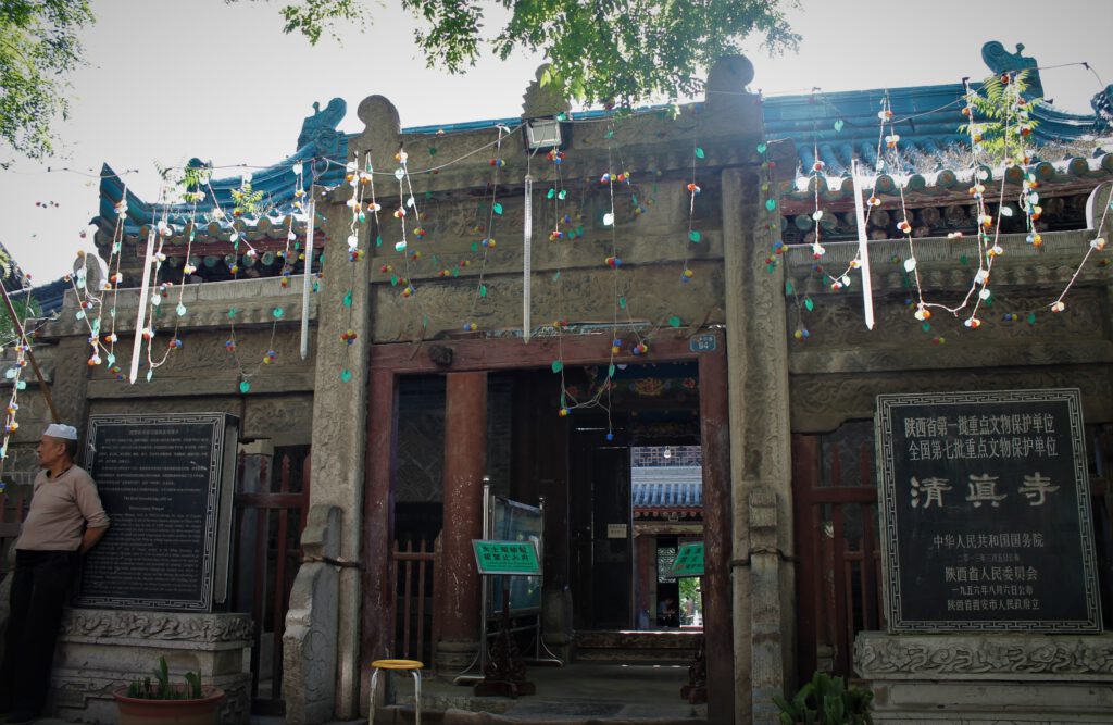 Eingang zur Daxuexixiang Moschee von Xi'an. Männer tragen oft eine weiße Kopfbedeckung.