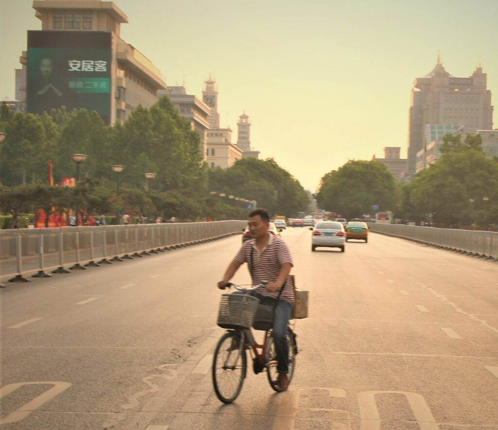 Einsamer Radfahrer auf großer Hauptverkehrsstraße in Xi'an. Im Gegenverkehr. 