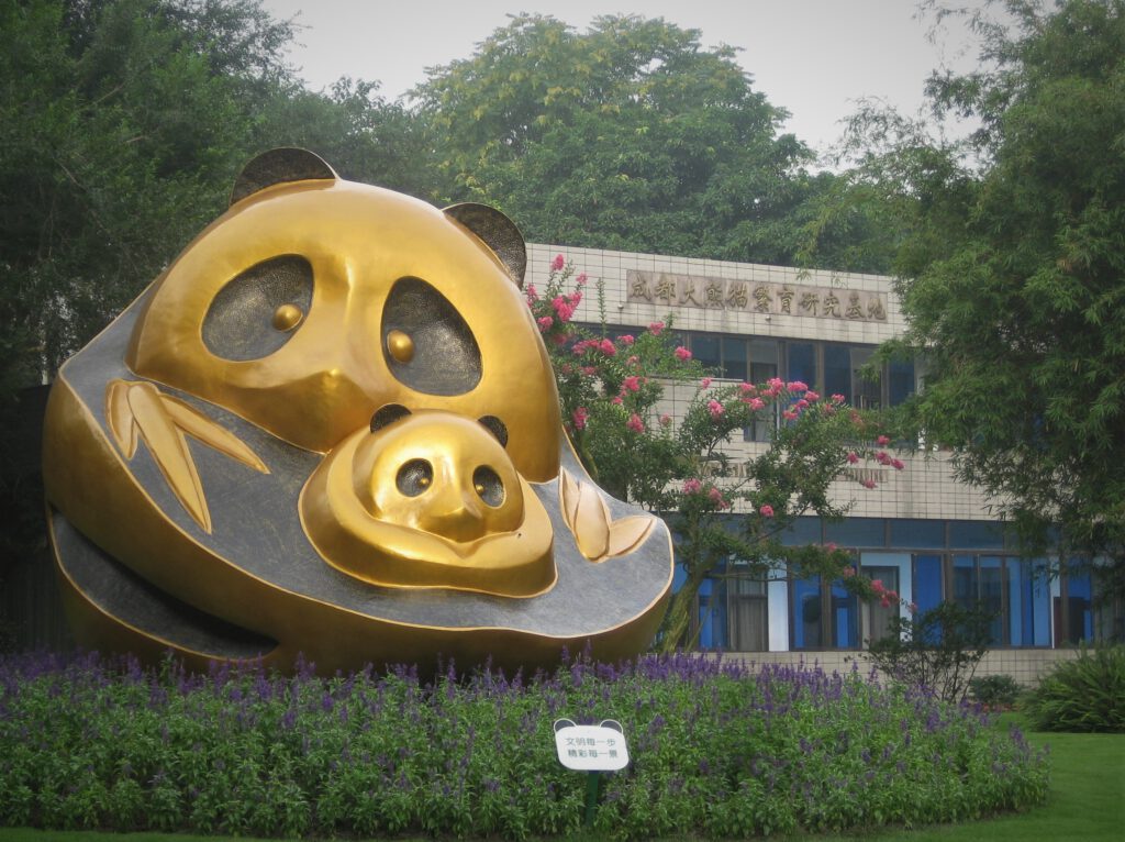 Eingang zur Panda-Aufzuchtstation von Chengdu. Im Vordergrund die goldene Panda-Skulptur mit Panda-Mutter und Panda-Baby 