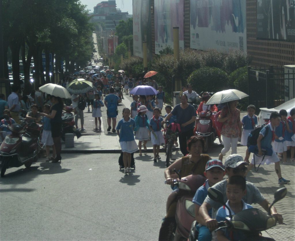 Belebter Bürgersteig mit Schülern in chinesischen Schuluniformen