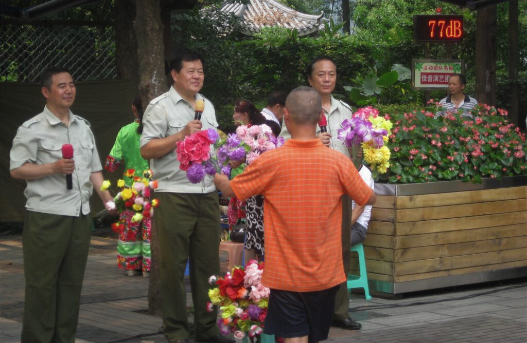 Ein Zuschauer bringt Sängern zwei Sträuße bunter Plastikblumen. 