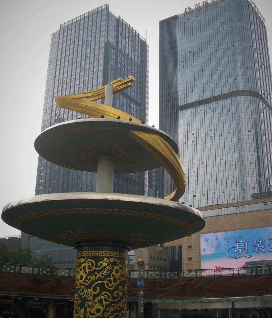 Fontänen-Säule auf dem Tianfu-Platz von Chengdu. Blick von der unteren Ebene des Platzes, hoch zu den umgebenden Wolkenkratzern. 