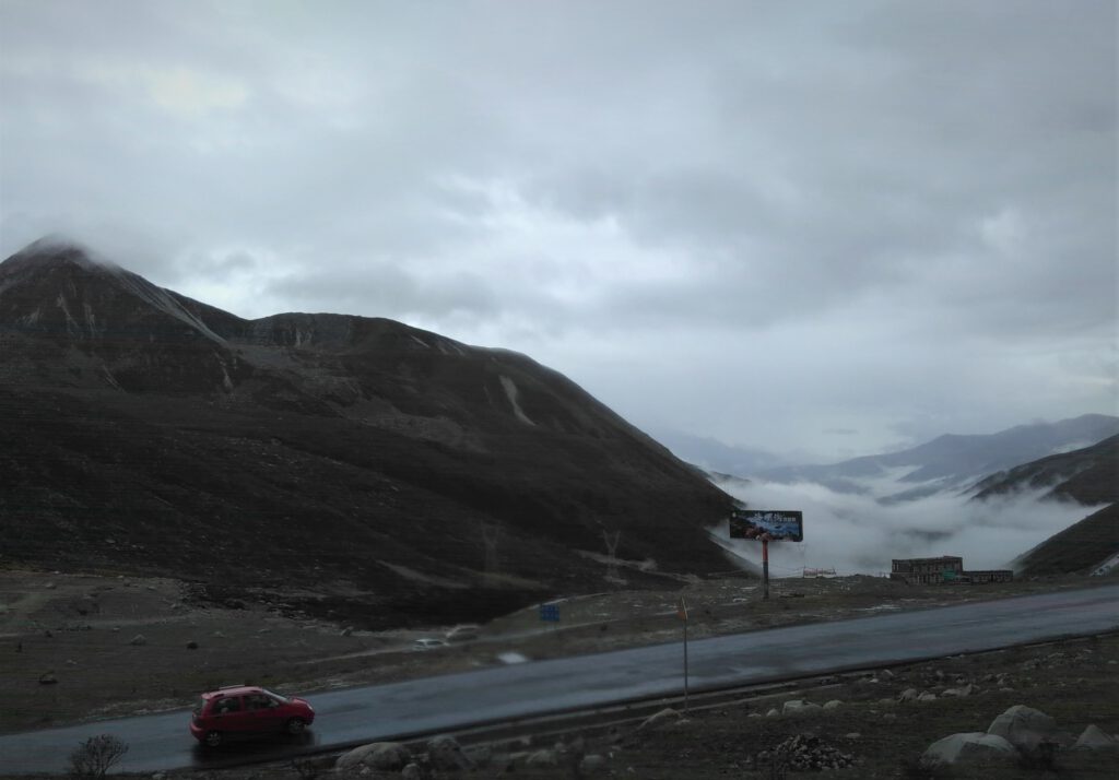 Blick auf eine Straße bei über 4000 Meter in Sichuan. Das Tal ist Wolken-bedeckt. 