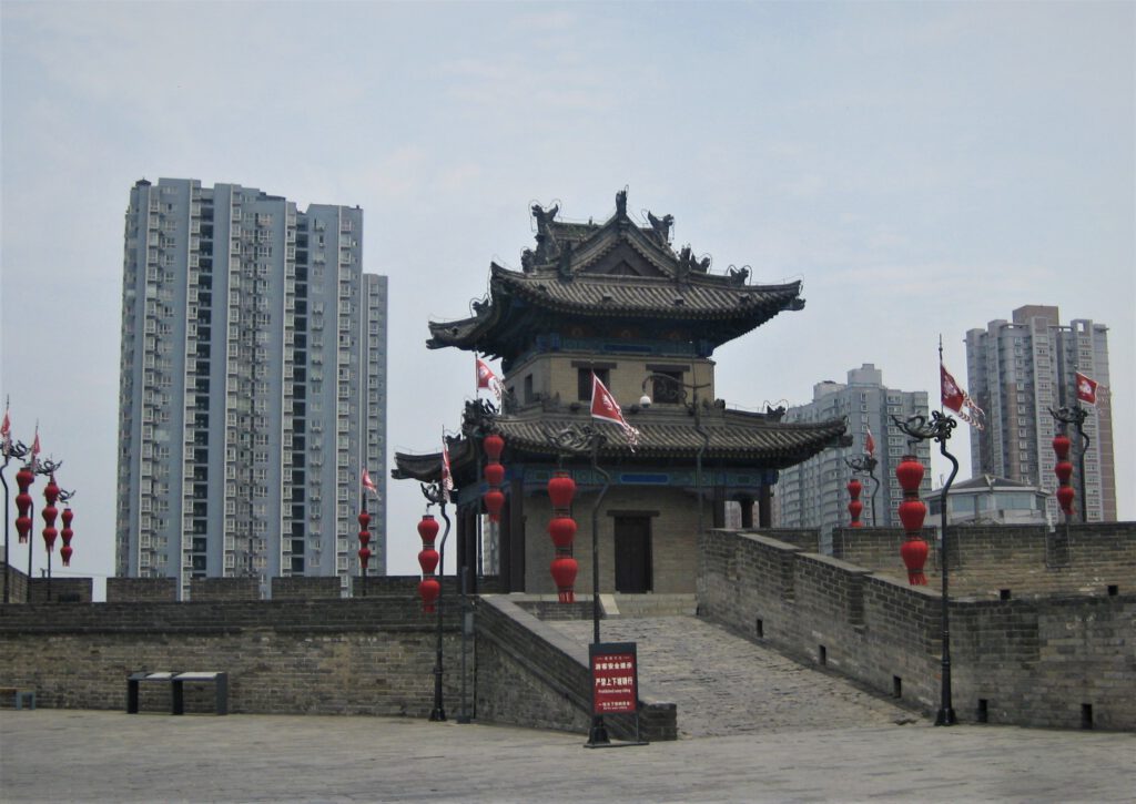 Turm der Stadtmauer von Xi'an vor dem Hintergrund großer Wohnhauskomplexe. 