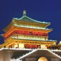 Bunt beleuchteter Glockenturm in Xi'an, China bei klarem Nachthimmel. Touristen auf den Terrassen.