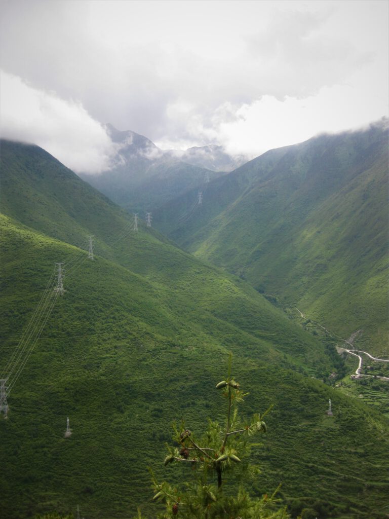 Grüne Berge von Kangding mit Srommaten und Gewitterwolken. 