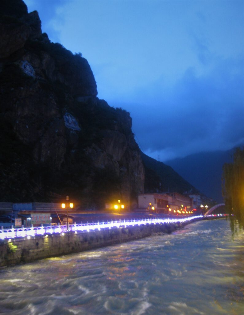 Beleuchteter Fluss bei Dämmerung in Kangding. 
