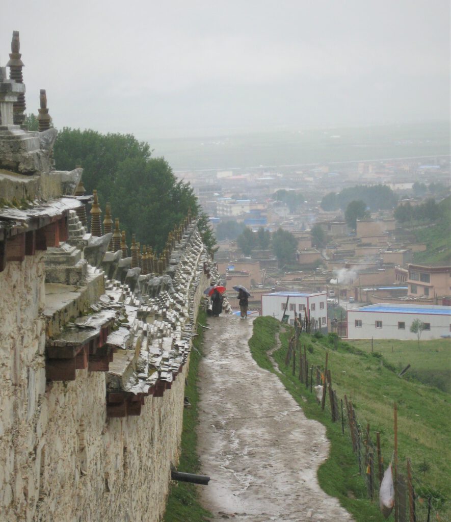 Rundweg um das Litang Kloster, entlang einer Mauer. Blick auf die Stadt. 