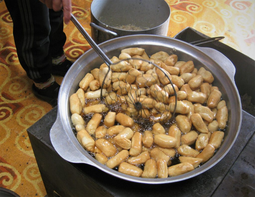 Mini-Brote frittieren in einem Topf mit Öl, auf einem Ofen in einem Ger.