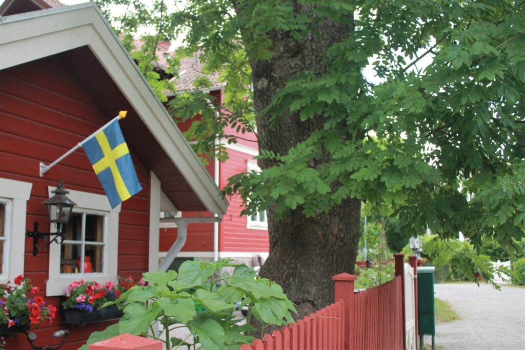 Rotes Holzhaus mit rotem Zaun auf Vaxholm. Eine schwedische Fahne hängt an der Fassade. 