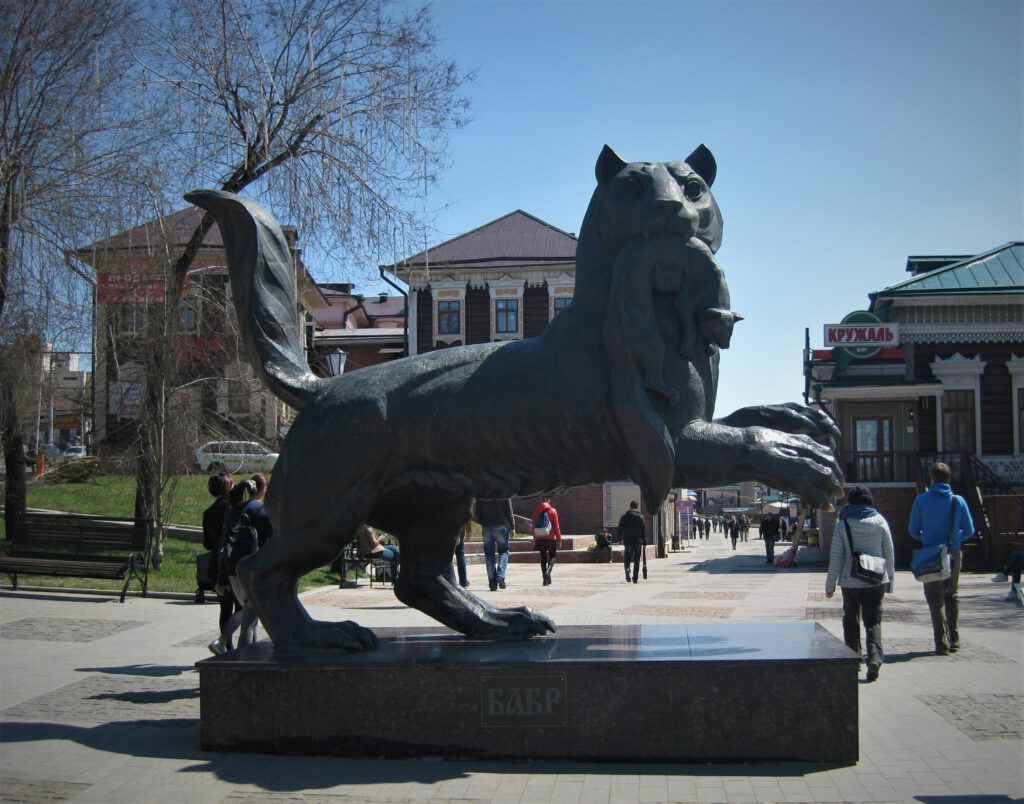 Skulptur des Babr vor dem Eingang zum Kvartal 130 von Irkutsk. Tiger mit Biberschwanz hat einen erlegten Zobel im Maul.Бабр