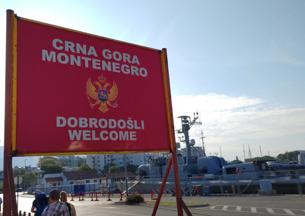 Großes rotes Straßenschild der roten montenigrinischen Flagge mit der Aufschrift "Crna Gora, Montenegro, Dobrodosli, Welcome".