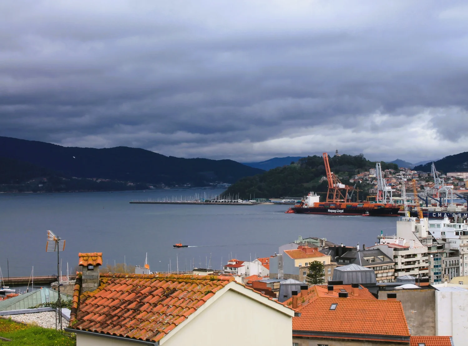 Blick richtung Hafen in der Ria Vigo, mit Frachtschiffen und Gebirgsstreifen in der Kulisse.