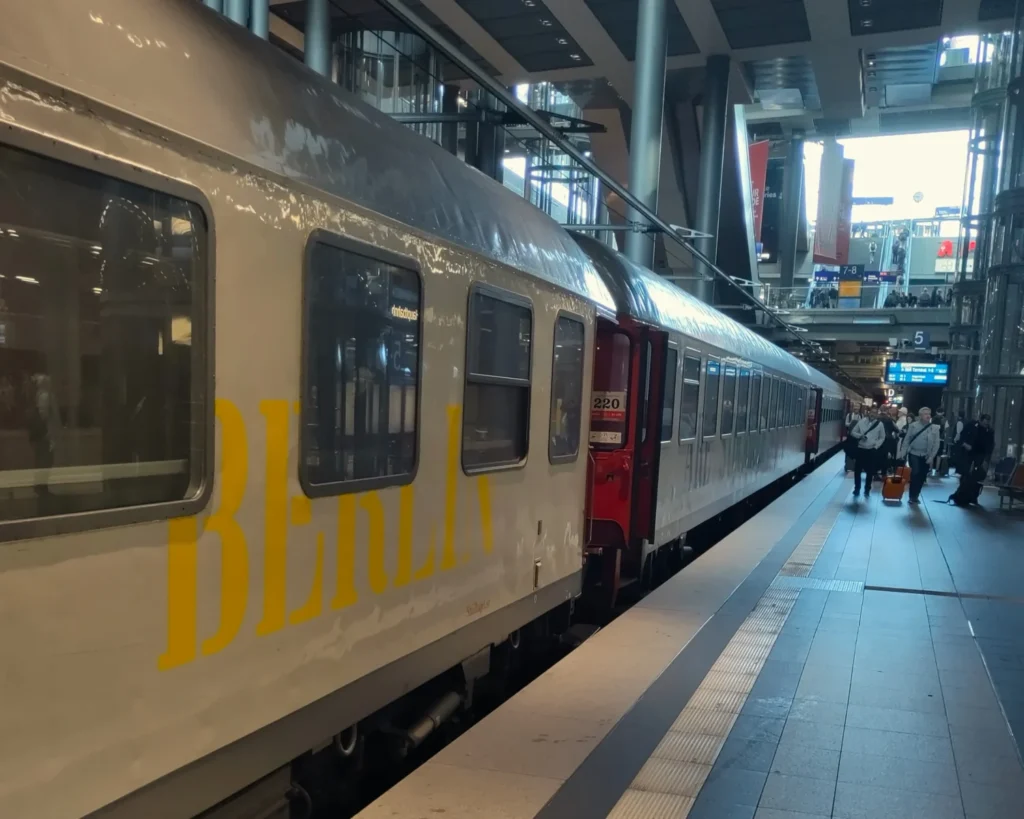Waggons des Snälltåget am Bahnsteig in Berlin Hauptbahnhof tief. Aufschrift "Berlin" in gelben Großbuchstaben auf dem vorderen Waggon.