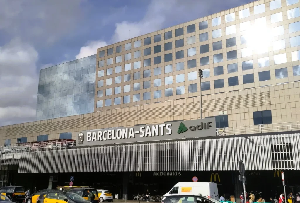 Frontansicht vom Bahnhof Barcelona Sants. Die Sonne reflektiert in den quadratischen Spiegelfenstern.