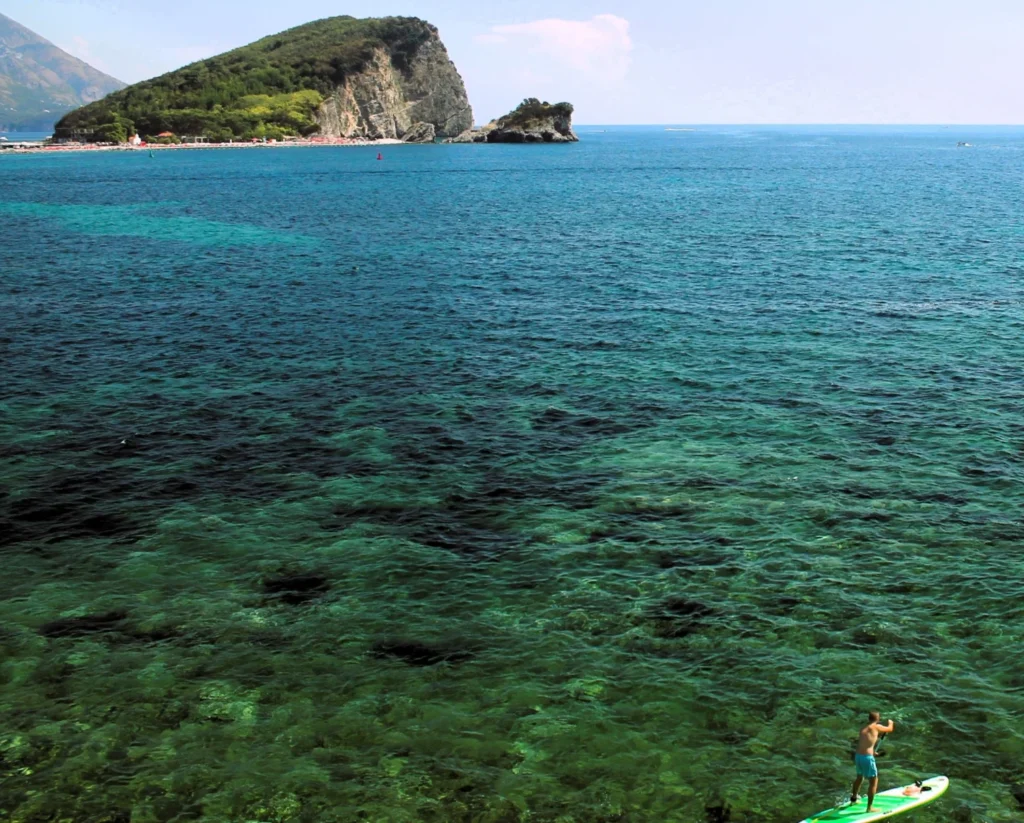 Türkises und blaues Wasser der Adria vor der Küste von Budva. Mit großem Felsen der Insel Sveti Nikola.