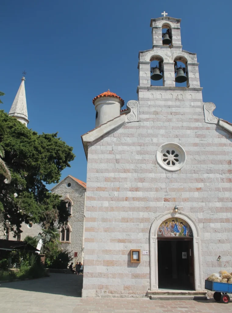 Vorderseite der Kirche der Heiligen Dreifaltigkeit in Budva Montenegro. Auf dem Giebel befinden sich 3 Glocken und ein Kreuz.