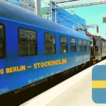Nachtzug Berlin - Stockholm. Blauer Waggon des SJ EuroNight am Bahnhof in Stockholm. Vorne die Lok. Fahne von Schweden rechts im Bild.