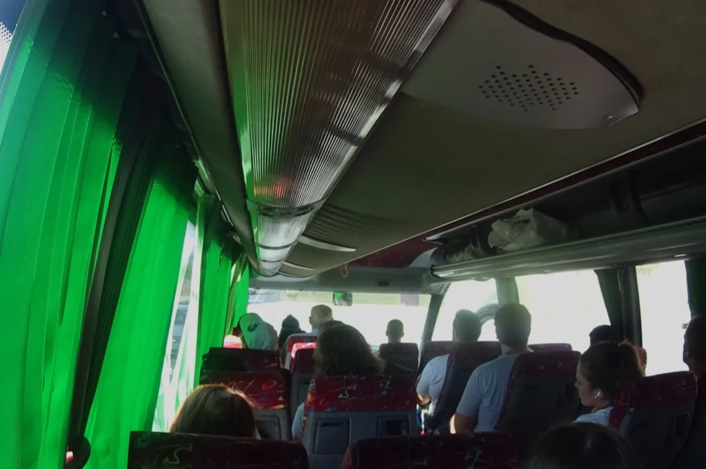 Gut besetzte Innenkabine im Bus Montenegro mit grünen Vorhängen.