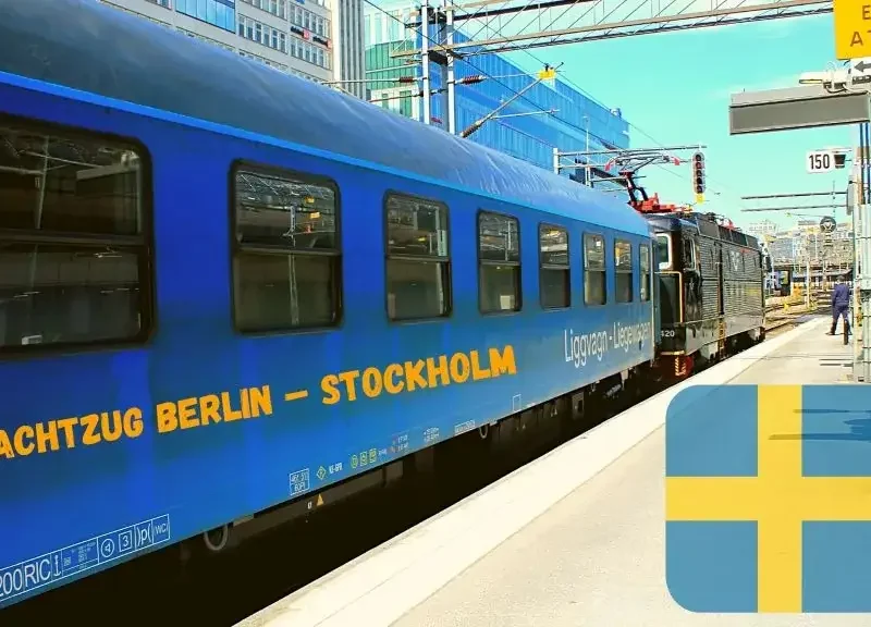 Nachtzug Berlin - Stockholm. Blauer Waggon des SJ EuroNight am Bahnhof in Stockholm. Vorne die Lok. Fahne von Schweden rechts im Bild.