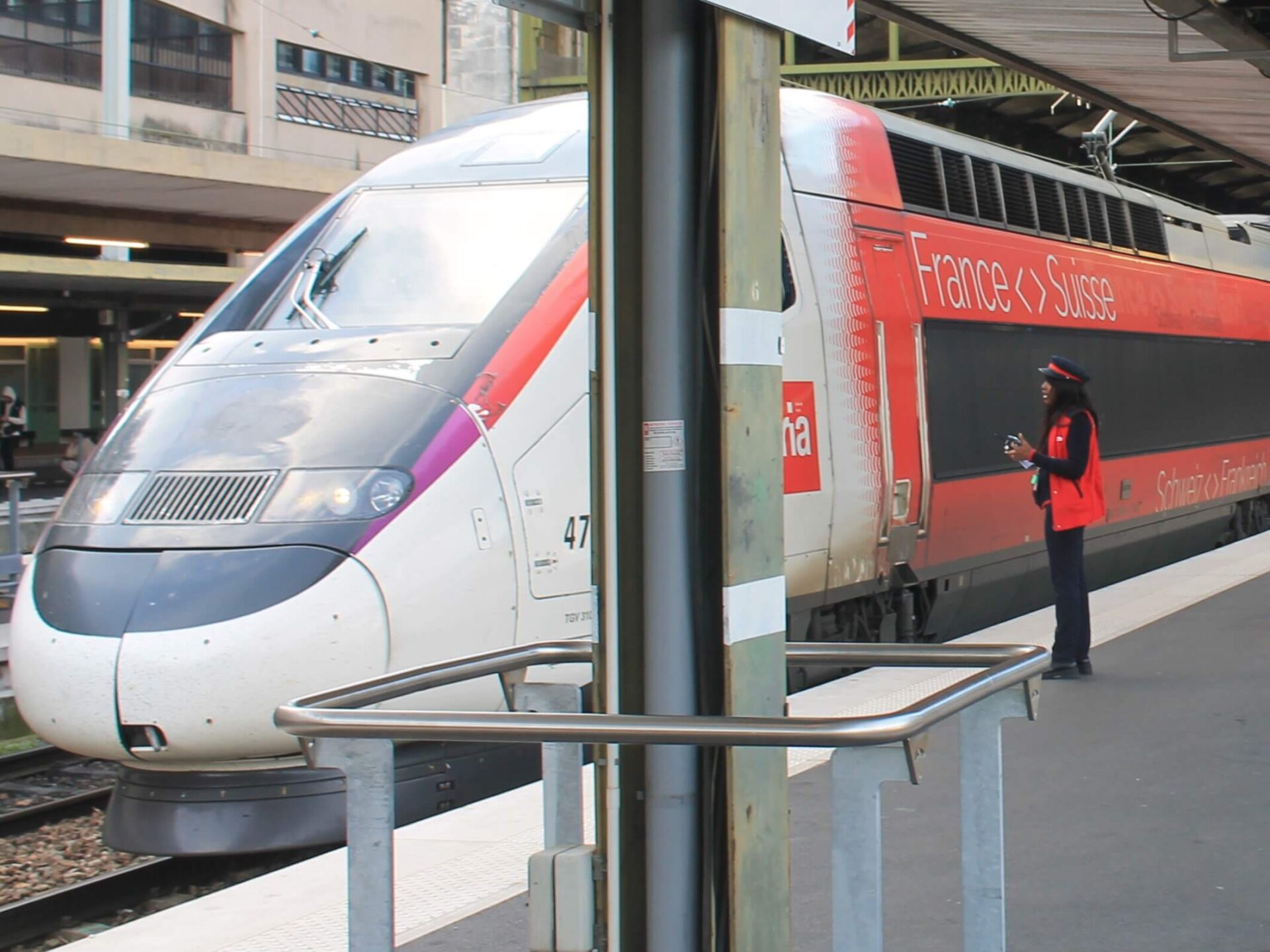 TGV Lyria auf dem Bahnsteig am Gare de Lyon in Paris. Neben dem Zug steht eine Schaffnerin, die mit der zugführenden Person spricht.