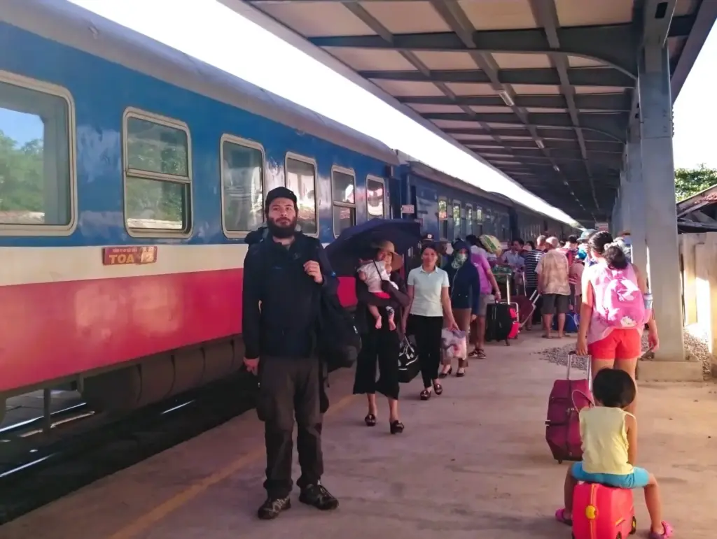 Bahnsteig in Vietnam mit Nachtzug und vietnamesischen Passagieren.  