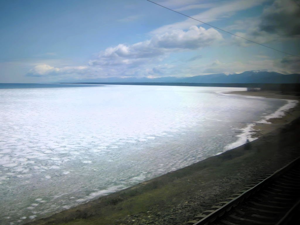 Das Eis schmilzt. Nahe der Küste liegen restliche Eisschichten des Winters auf dem Baikalsee neben den Eisenbahnschienen.
