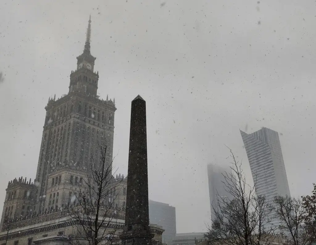 Kulturpalast Warschau im Winter 2023, im Bild mit einem Obelisken und Hochhäusern der City.  