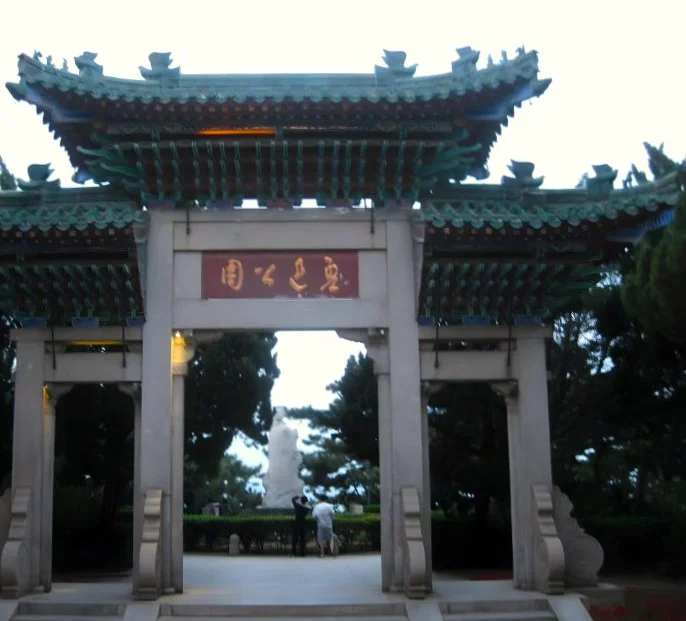 Traditionelles chinesisches Tor mit geschwungenen, grünen Dächern. Chinesische Beschriftung.
