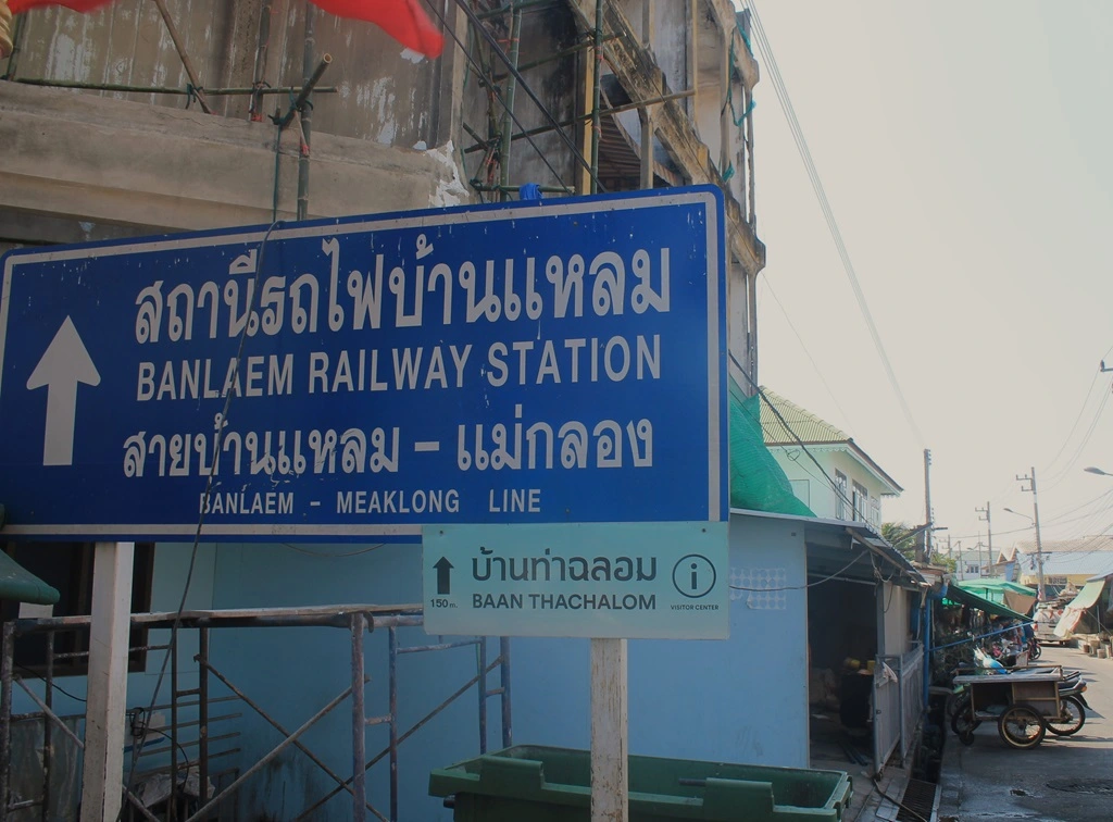 Blaues Straßenschild in Tha Chalom zeigt die Richtung zum Bahnhof Ban Laem (Ban Laem Railway Station) an. 