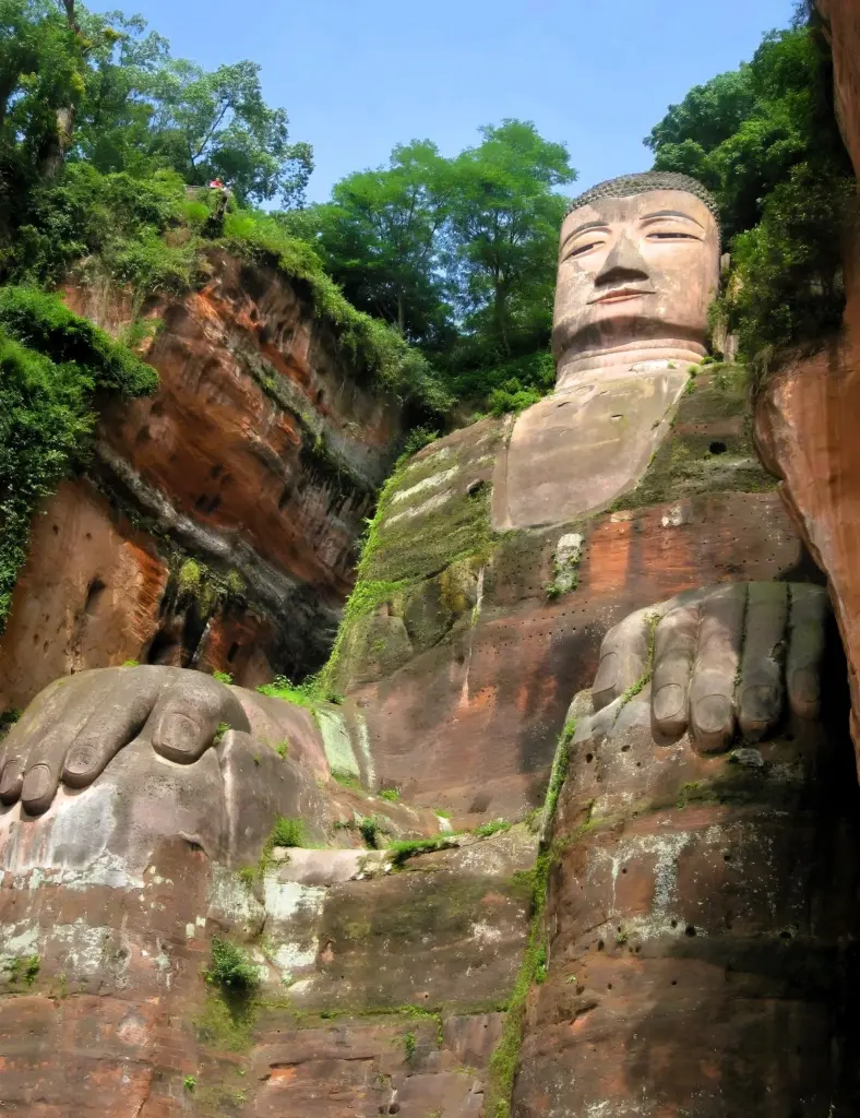 Leshan Buddha – der sitzende Buddha in Leshan, von vorne fotografiert. In roten Fels gemeißelt und mit Moos bewachsen. 