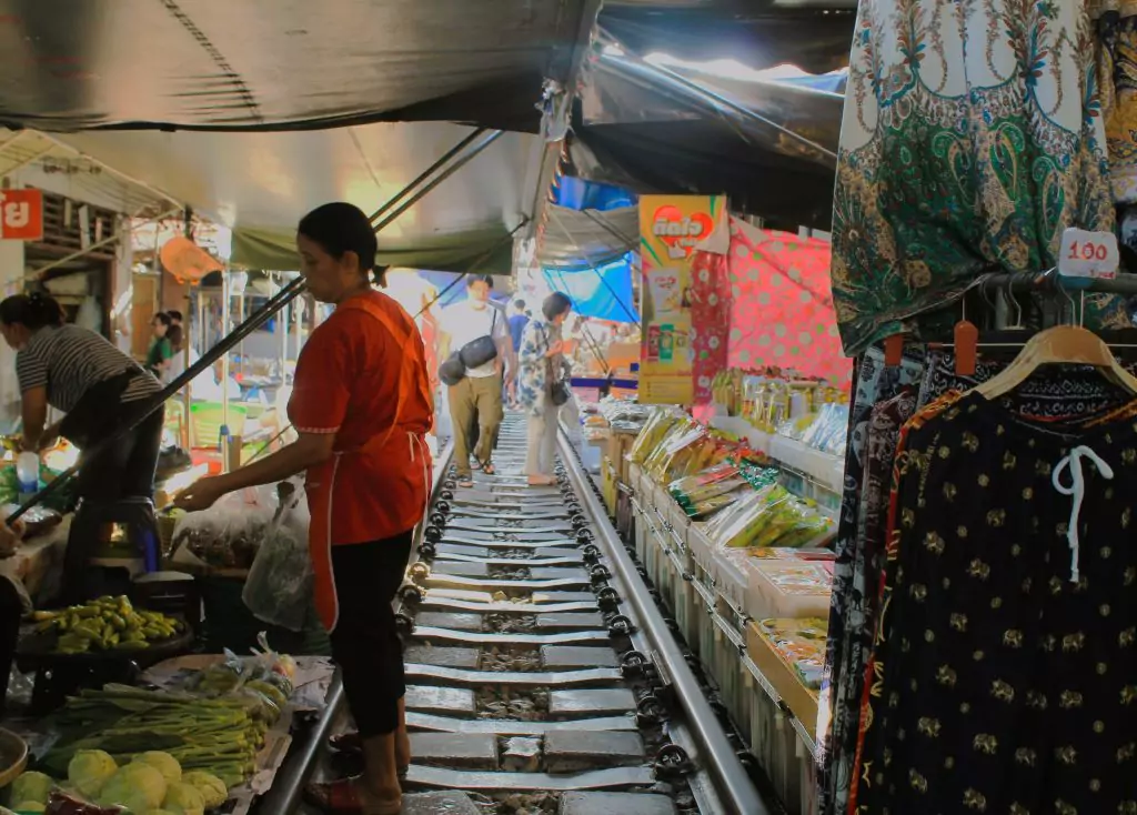 Mae Klong Markt. Verkäuferin auf den Eisenbahnschienen zwischen den Marktständen. 