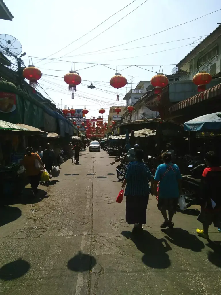 Marktstraße in Maha Chai. Rote chineische Laternen hängen an Leinen über der Straße. 