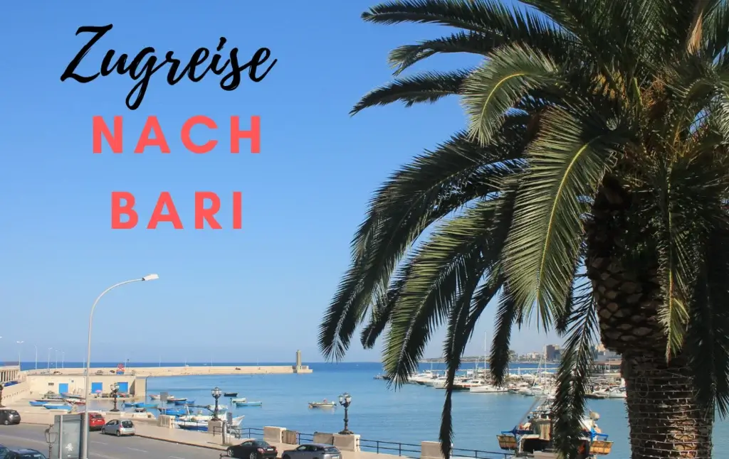 Blick von Via Venezia auf Meer und Bari Strand. Palme liegt über halbem Bild. Mole ragt vom Hafen ins Meer. Blauer Himmel. Zugreise nach Bari