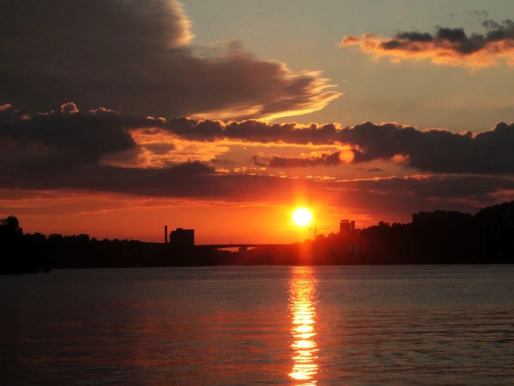 Rote und orangene Farben im Himmel über  Stockholm. Die Sonne spiegelt sich im Wasser. 