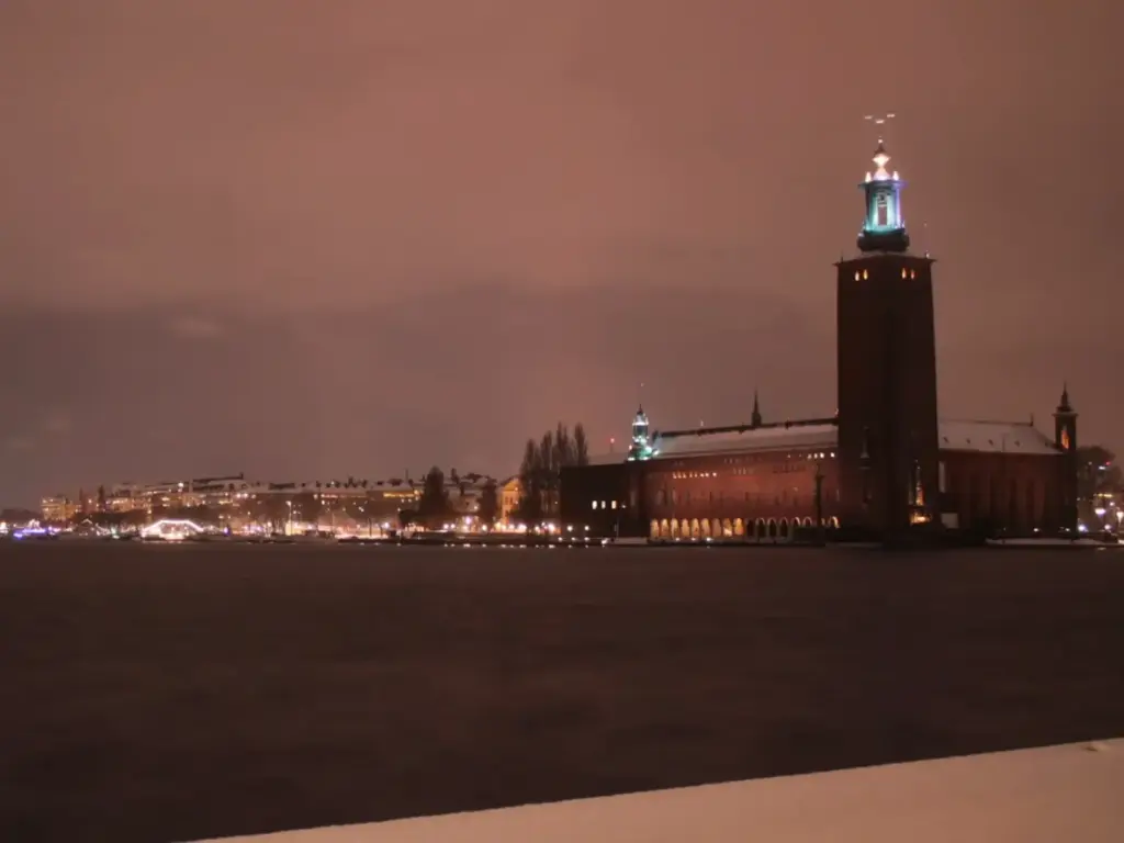 Stockholm Stadshuset von Riddarholm aus. Nachtaufnahme im Winter. Ufer von Kungsholmen beleuchtet.