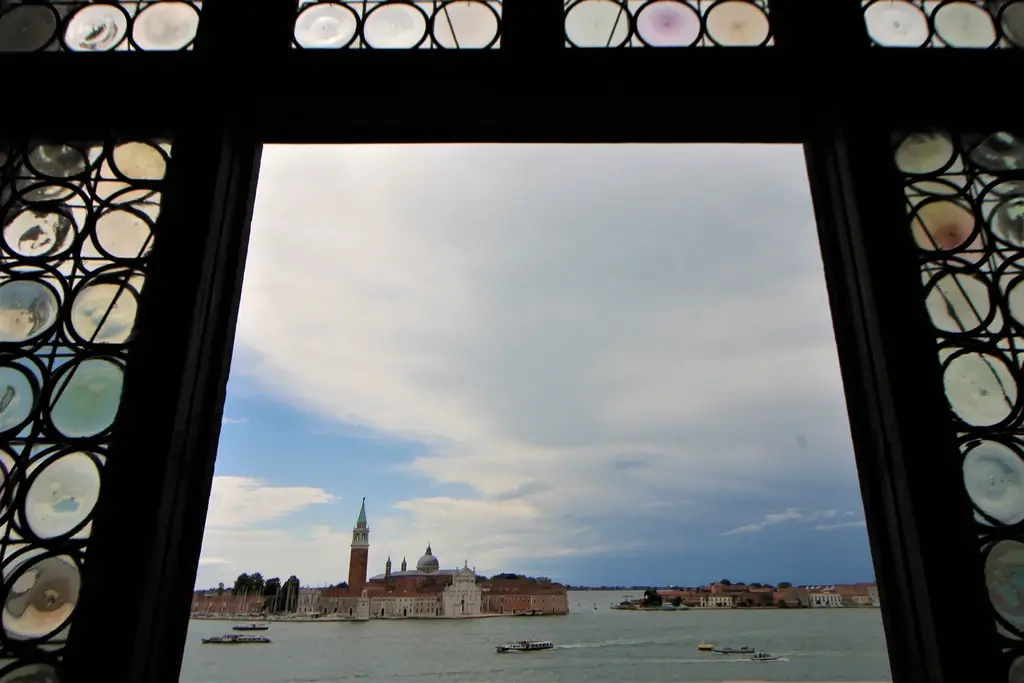 Blick durch Fenster mit Buntglasscheiben auf die Lagune von Venedig mit der San Giorgio Maggiore-Kirche. 