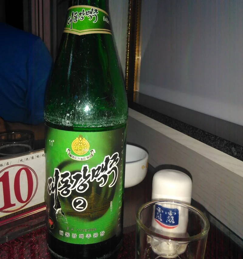 Grüne Flasche mit Taedonggang Bier aus Nordkorea auf dem Tisch des Restaurants.