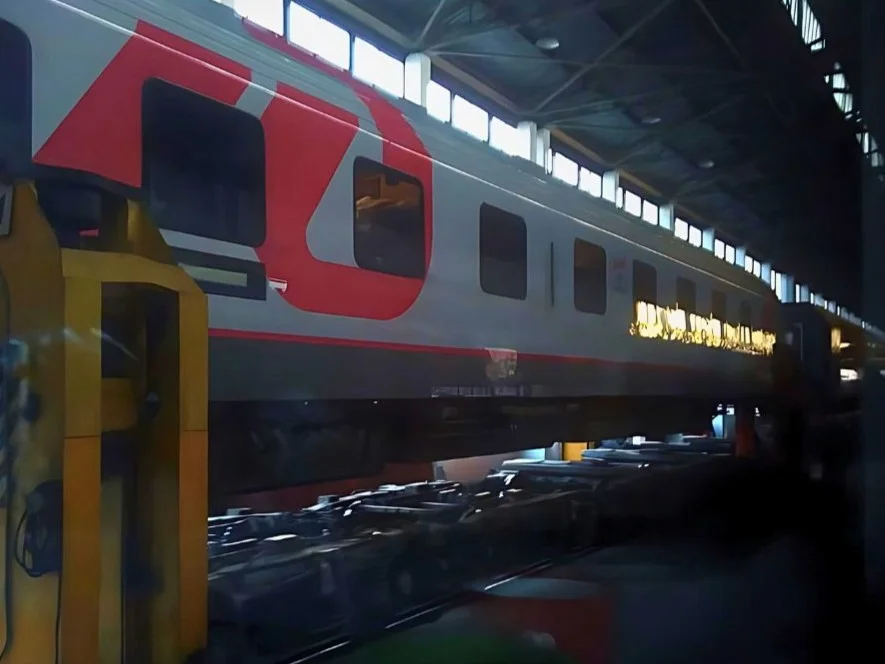 Grauer Waggon der russischen Eisenbahn während der Umspurung. Gesamter Wagen angehoben über den Schienen.