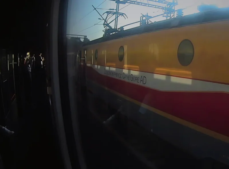 Lokomotive der Eisenbahngesellschaft Montenergo. ZPCG. Signaturfarben orange, weiß, rot. Aufschrift "Željeznički prevoz Crne Gore". Durch Zugfenster fotografiert.