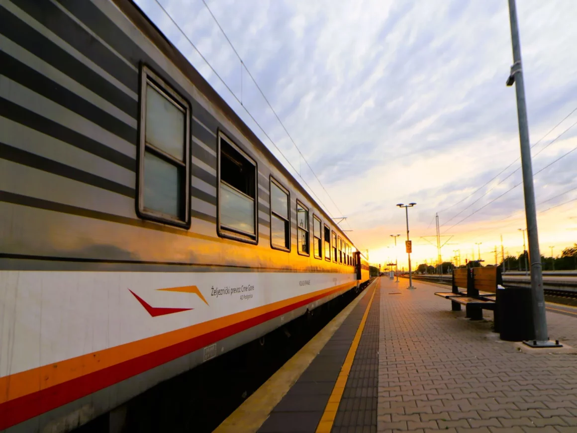 Alte Waggons der Eisenbahn von Montenegro stehen am Bahnsteig vor dem Sonnenuntergang bei leicht bewölktem Himmel.