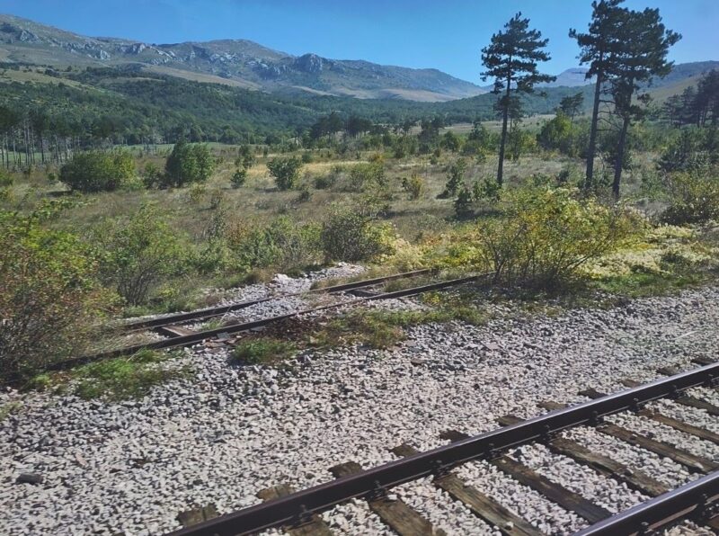 Eisenbahnschienen im Tal einer grünen Karstlandschaft in Kroatien.