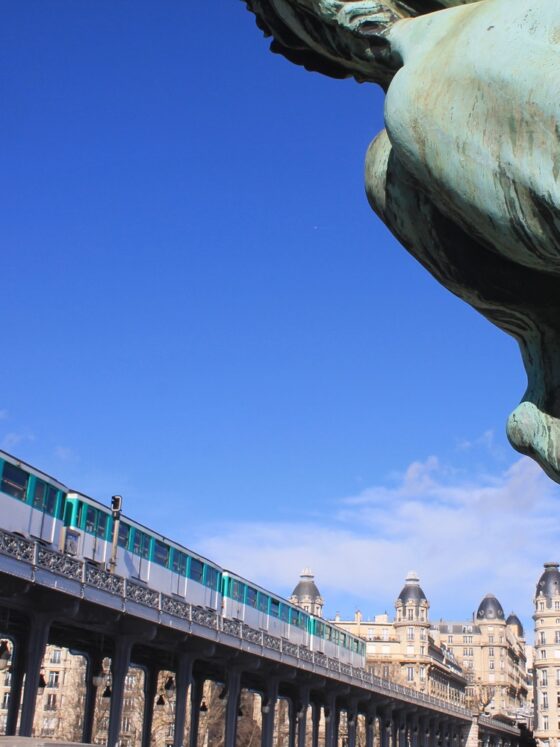 Pariser Metro fährt auf einer Trasse über die Bir Hakeim Brücke. Davor das Hinterteil einer bronzenen Pferdestatue.