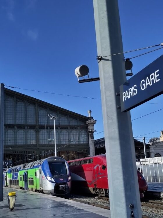 Bahnhofsschild mit der Aufschrift "Paris Gare du Nord" am Bahnsteig hinter der Empfangshalle.