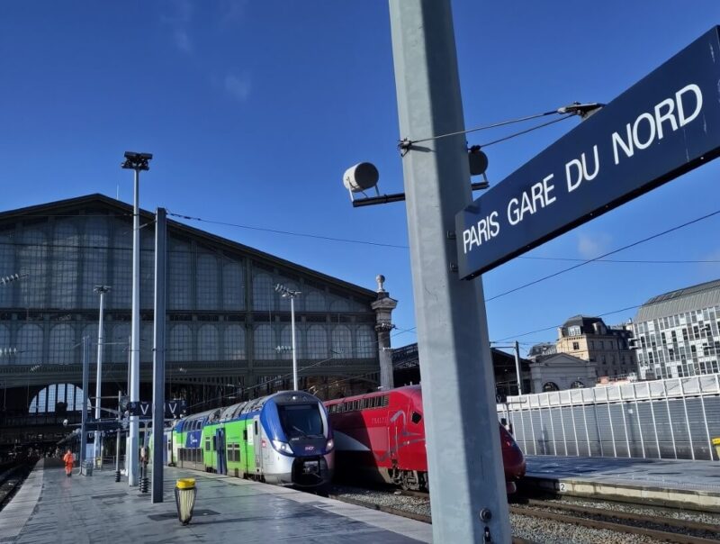 Bahnhofsschild mit der Aufschrift "Paris Gare du Nord" am Bahnsteig hinter der Empfangshalle.